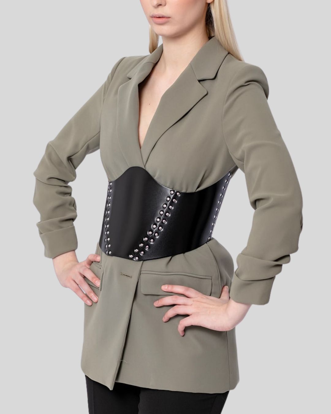 Angled side view of black leather corset belt worn over an oversized jacket