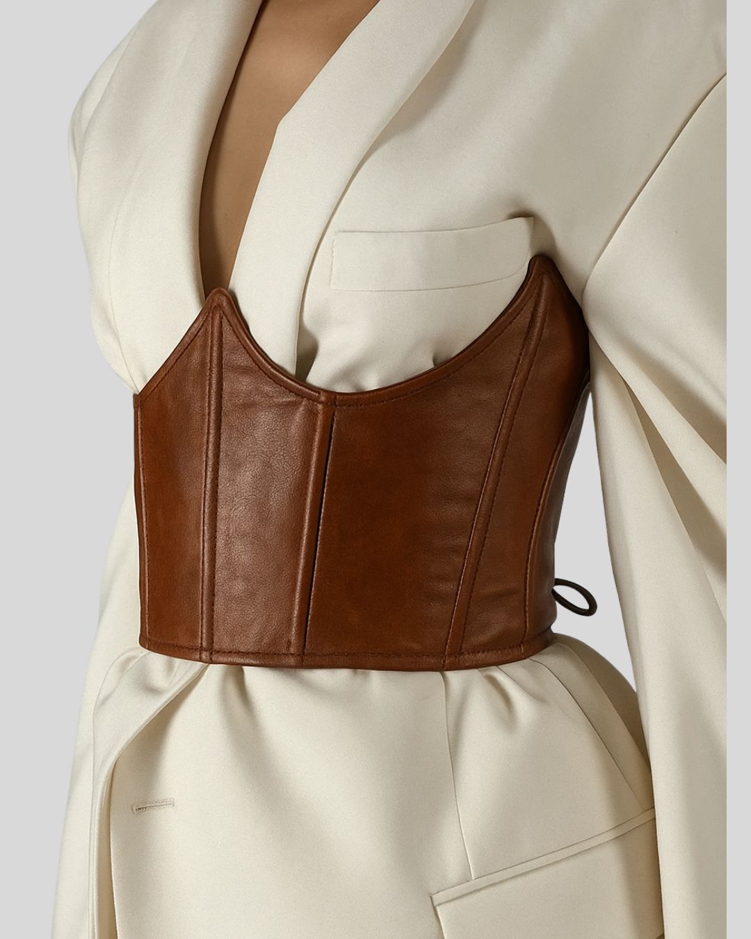 front close-up of brown leather corset belt on white blazer