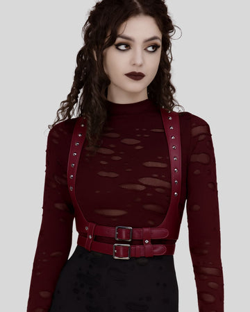 model wearing burgundy leather body harness with silver studs over distressed burgundy top