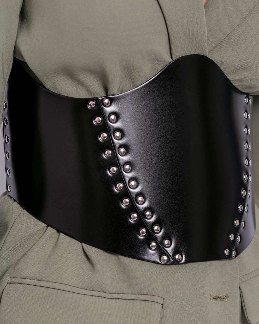 Close-up of silver rivets and gloss finish on black leather corset belt