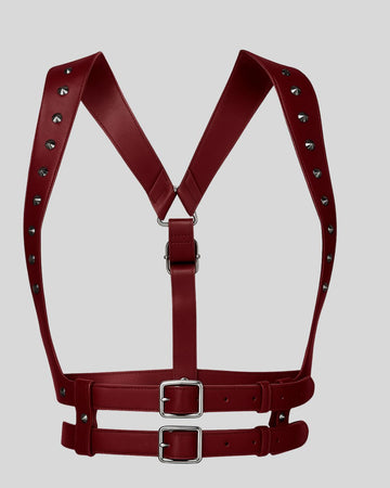 burgundy leather harness with silver buckles and studs displayed flat