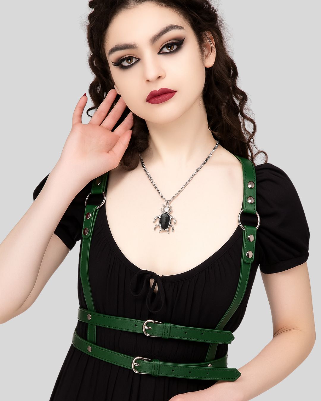 woman wearing green leather body harness over black dress
