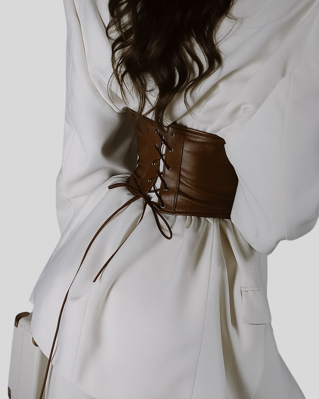 front close-up of brown leather corset belt on white blazer