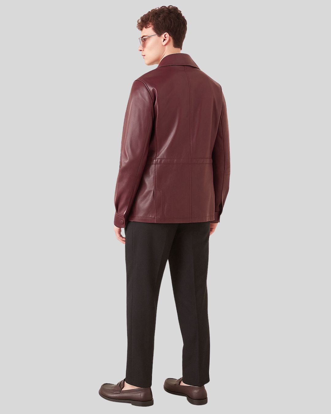 Man wearing a maroon leather jacket on a gray background