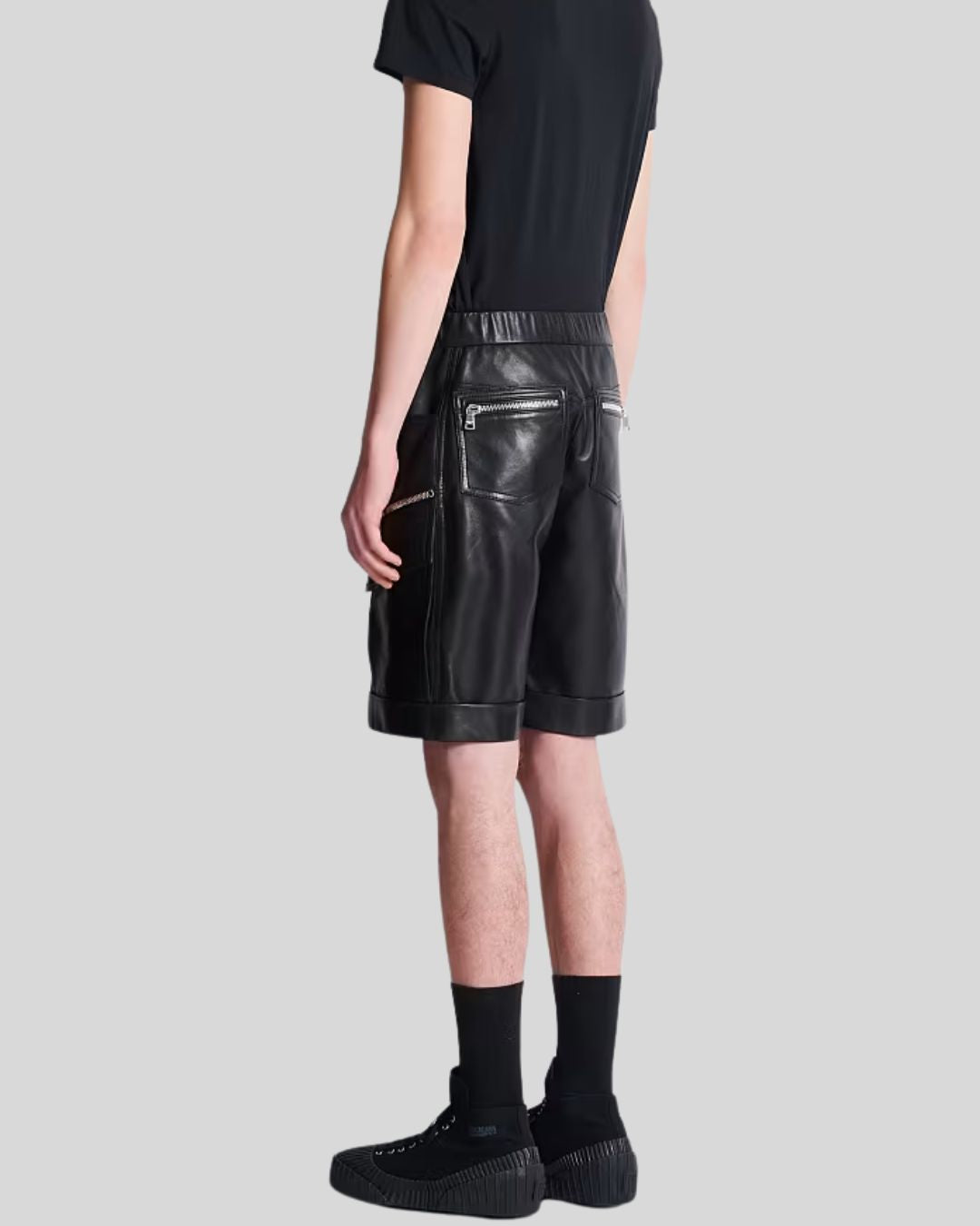 Men wearing black leather cargo shorts with zipper pockets and rolled hems