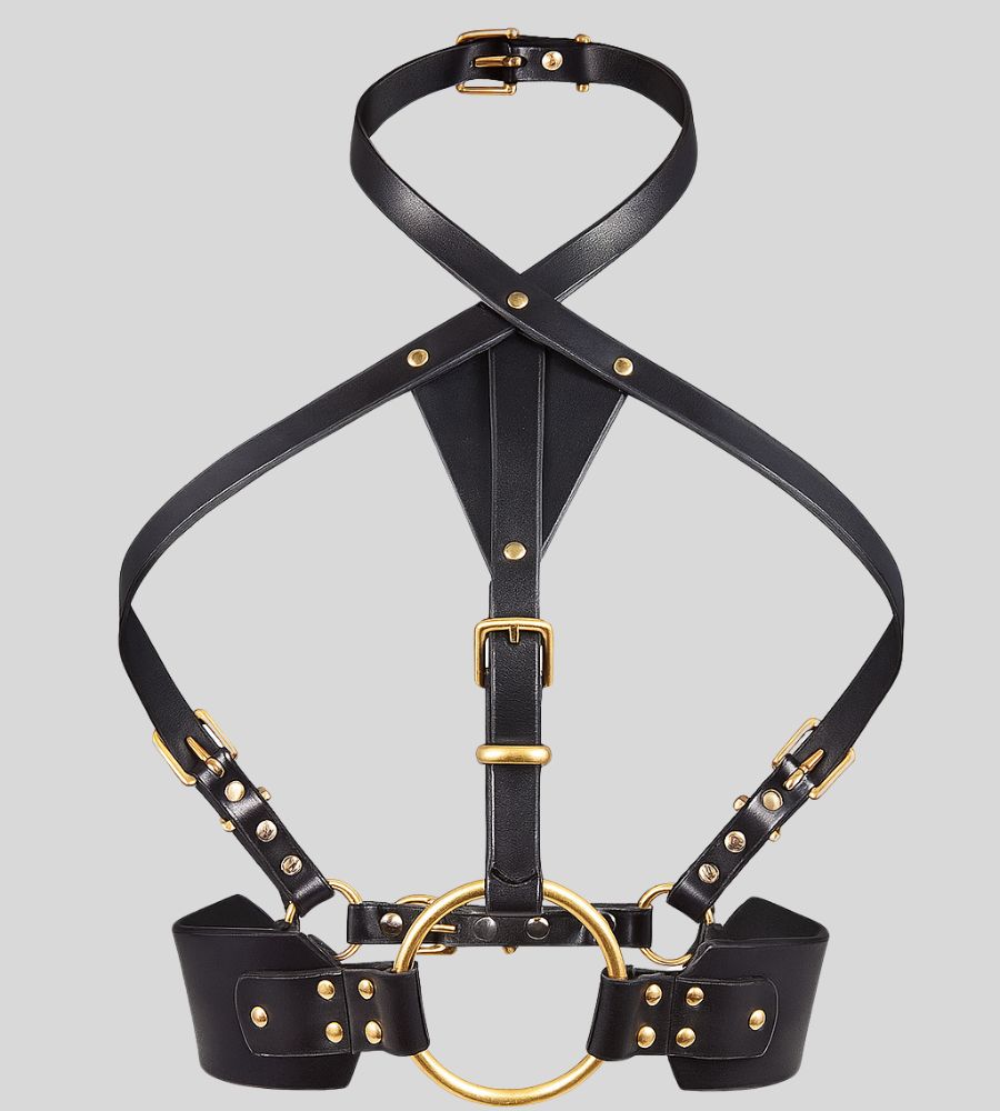 black leather harness with gold ring laid flat