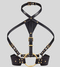 black leather harness with gold ring laid flat
