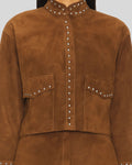 close up view brown suede jacket with studded details on a plain background