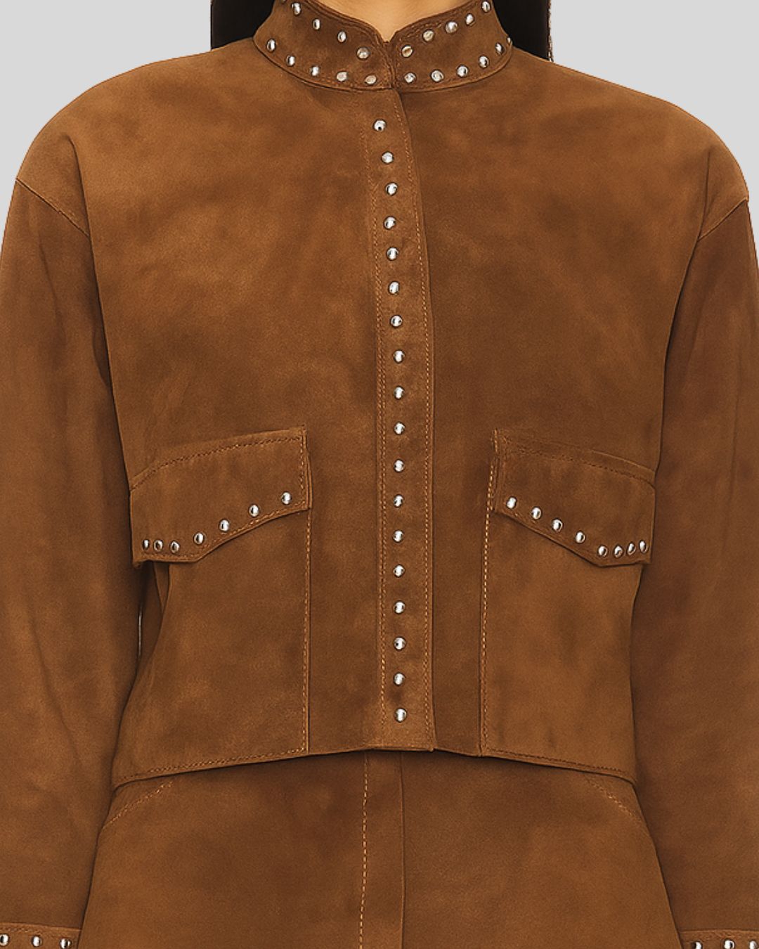 close up view brown suede jacket with studded details on a plain background