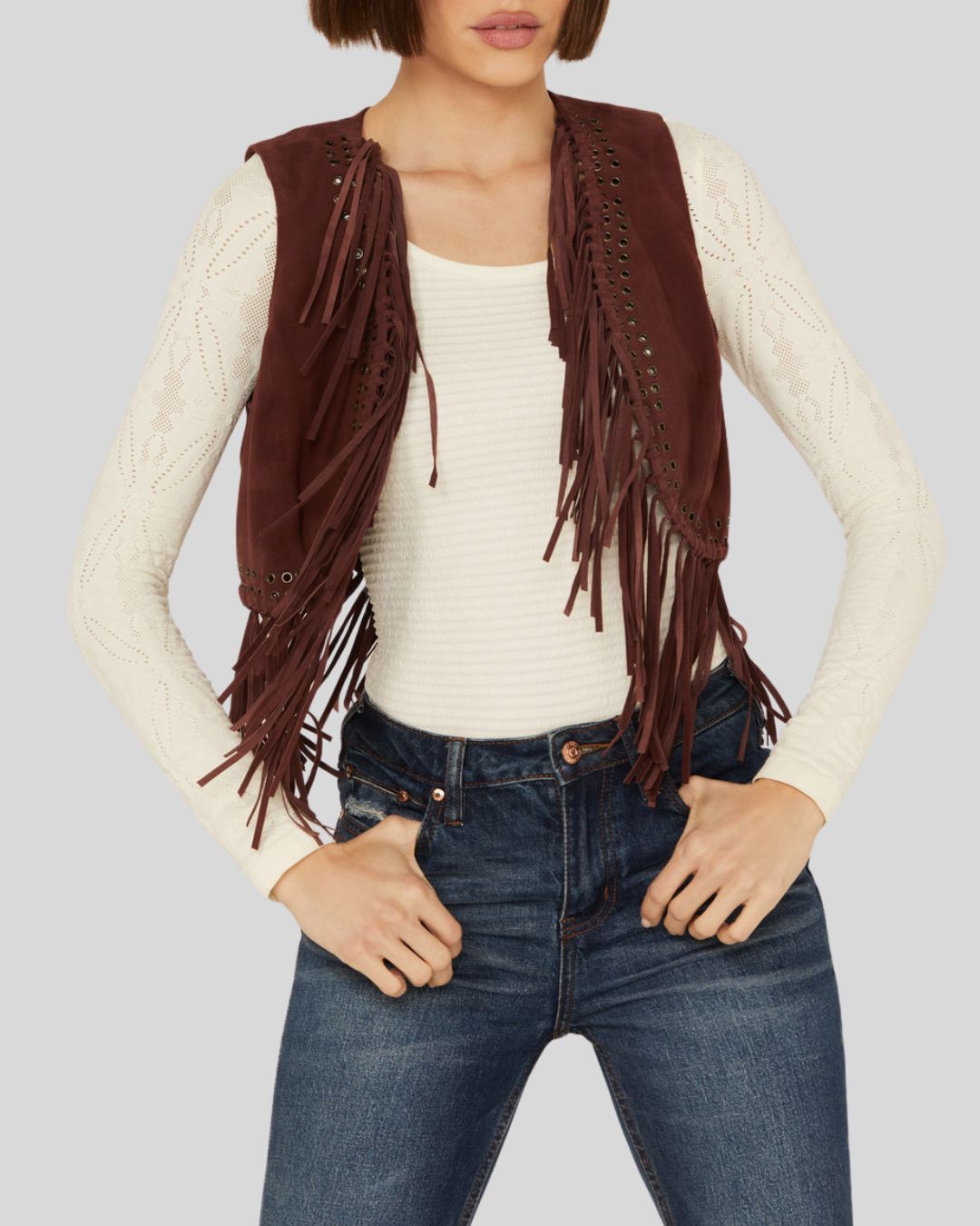  Woman wearing a burgundy suede fringe vest with grommet detailing, front view.
