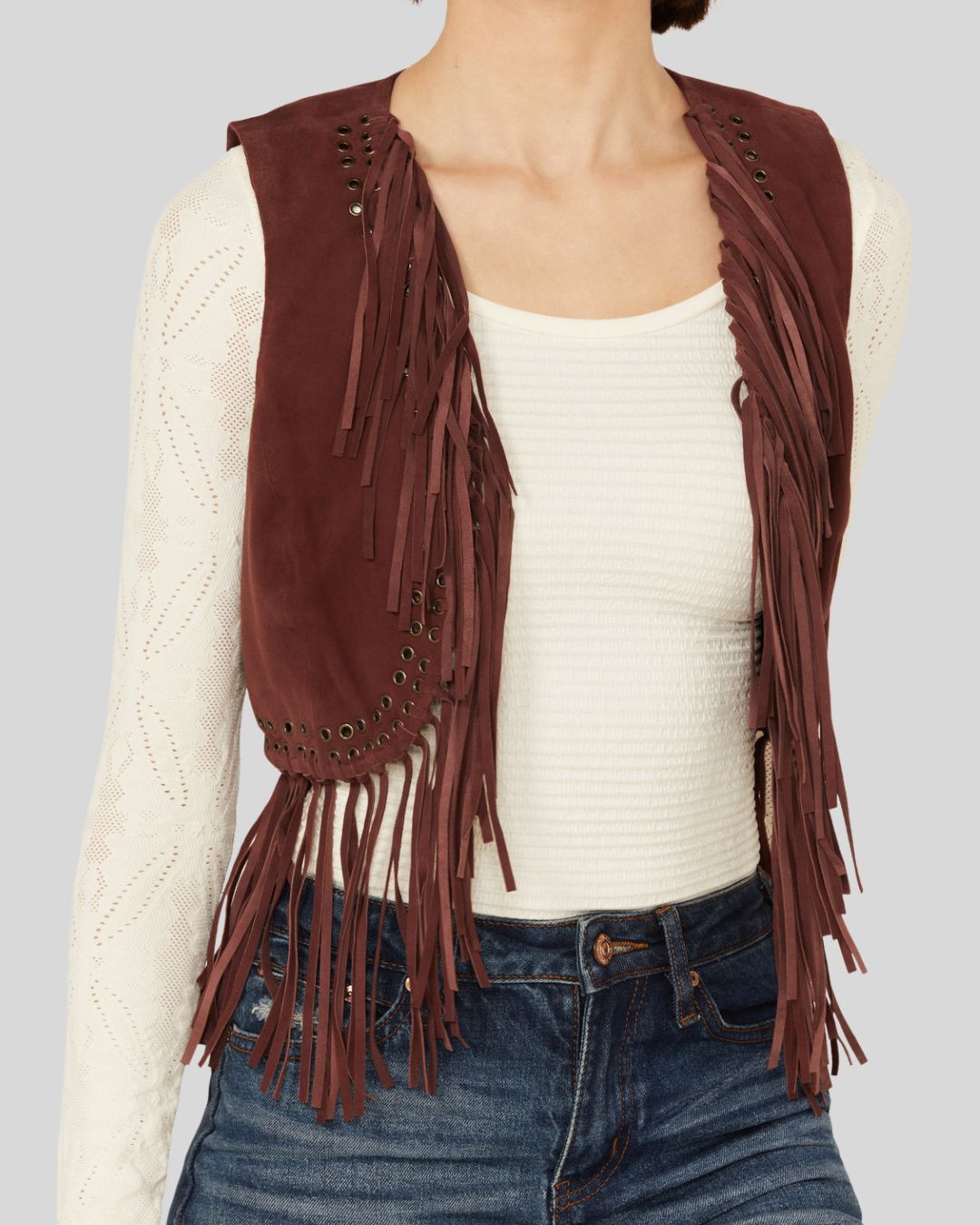  Woman wearing a burgundy suede fringe vest with grommet detailing, front view.
