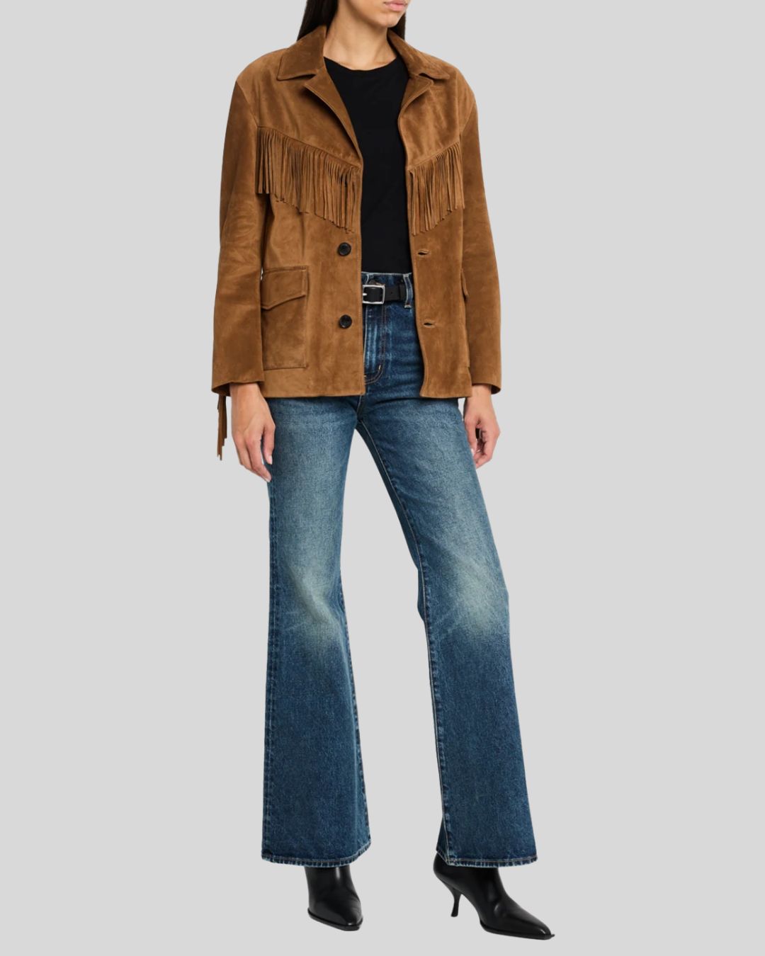 Model wearing a brown suede fringe jacket styled with flared jeans and boots.
