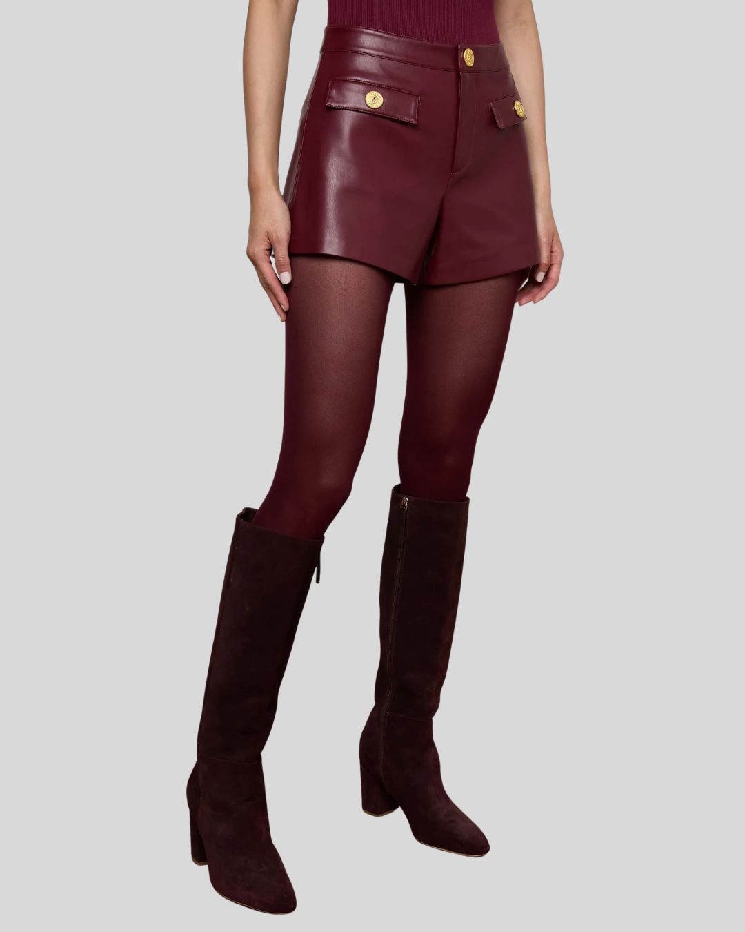 Side angle of women’s high waisted burgundy leather shorts with gold buttons