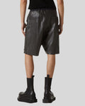 Person wearing black leather shorts and boots on a white background