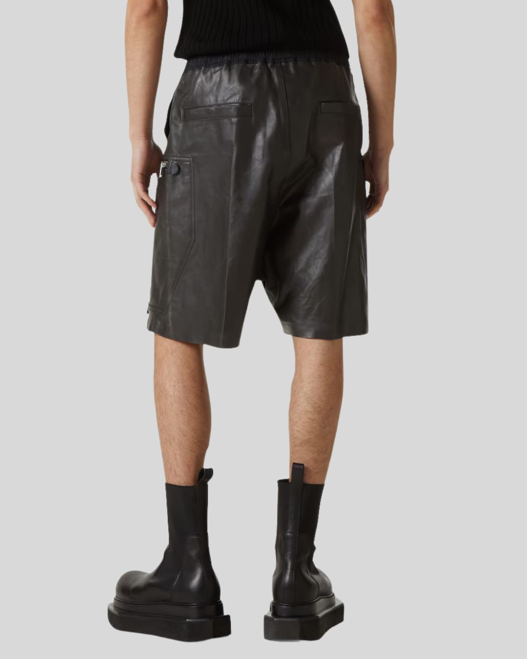Person wearing black leather shorts and boots on a white background