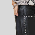 side close-up of metal studs on black leather pants