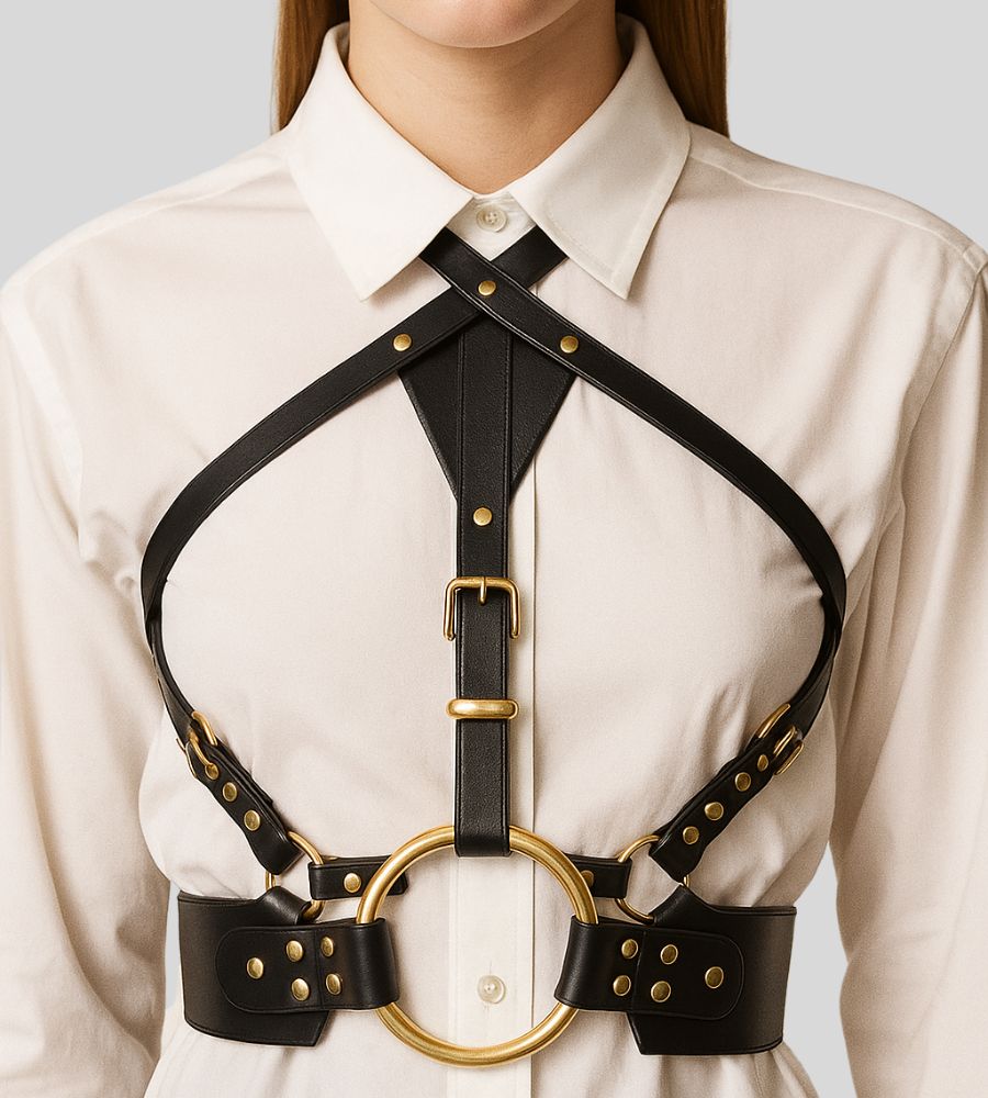 black leather harness with gold ring laid flat
