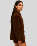 Side view of a women's dark brown suede utility jacket worn with matching shorts
