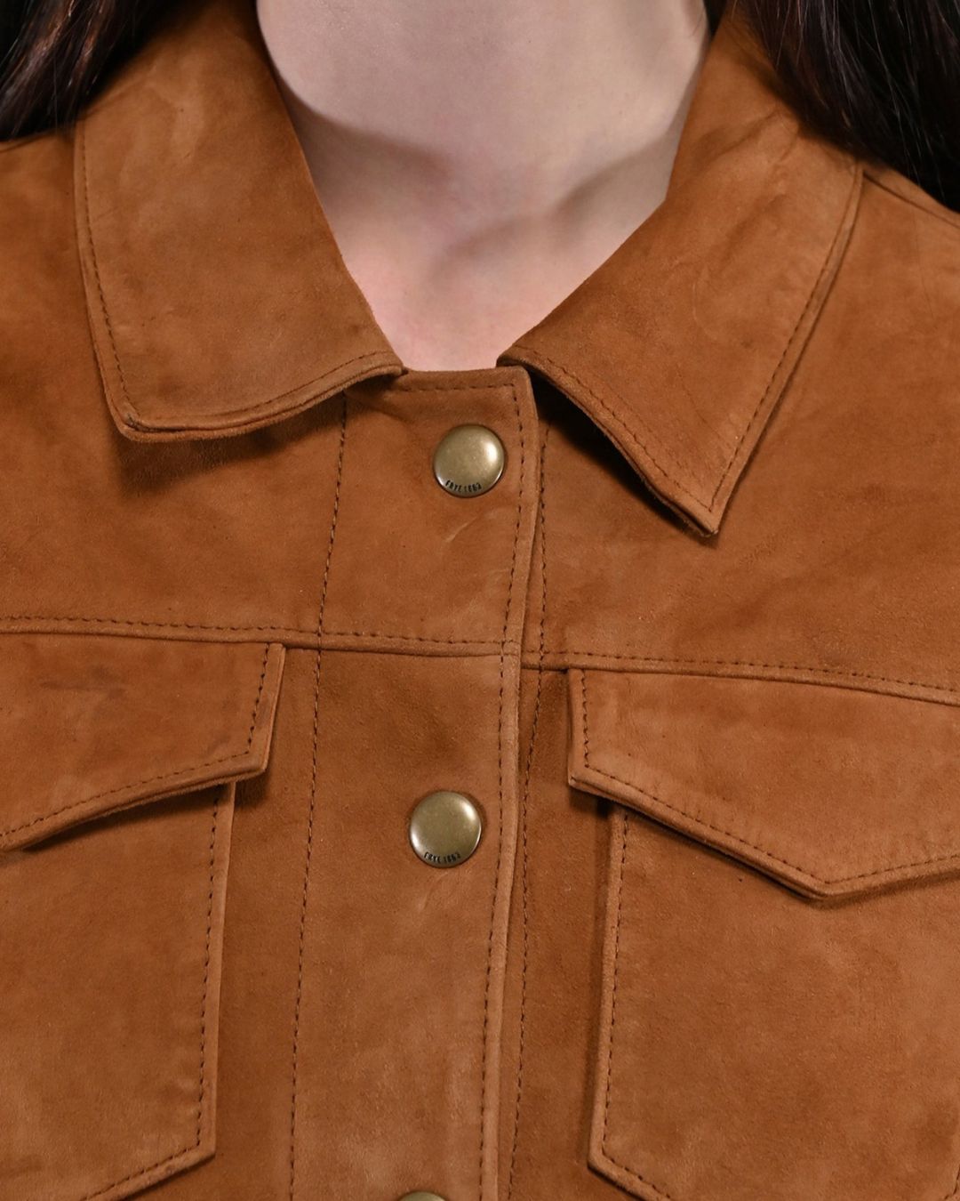  Close-up of collar and brass snap on tan suede fringe jacket

