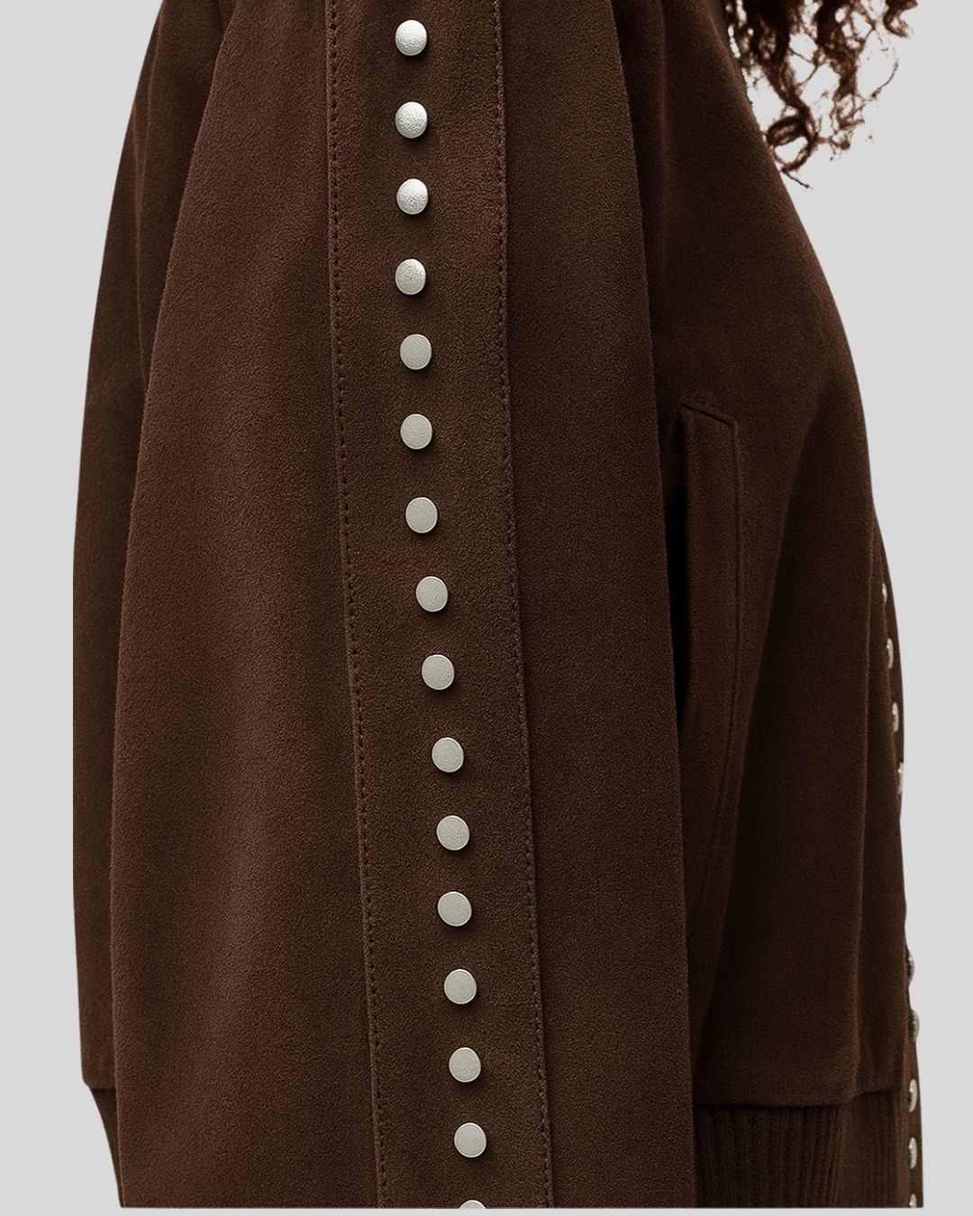 Close-up of studded sleeve detail on brown suede bomber